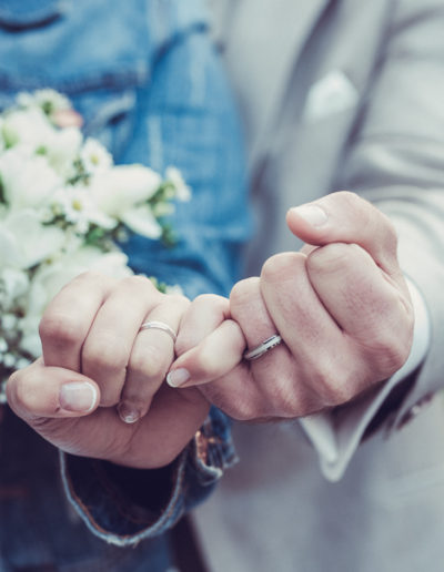 Éclat des alliances : Gros plan sur les mains des mariées, mettant en valeur leurs précieuses alliances.