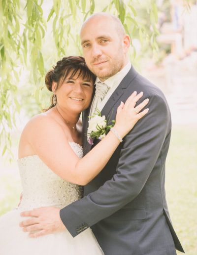 Mariés sous un saule pleureur, posant fièrement et souriants pour le photographe