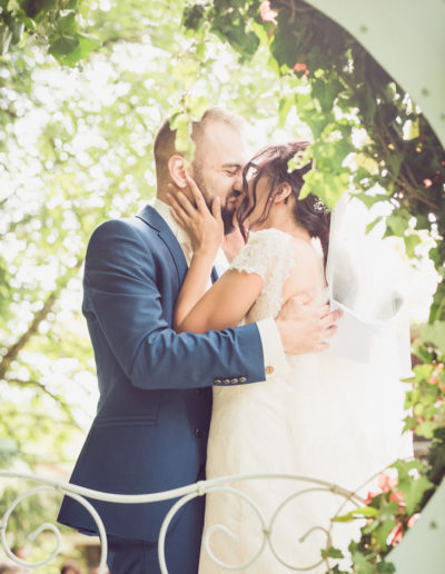 Mariage sous une arche de fleurs - Couple s'embrassant lors de la cérémonie laïque en Haute-Savoie.