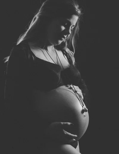 La future maman porte un bola de grossesse en argent, un bijou traditionnel pour les femmes enceintes qui émet une mélodie apaisante pour le bébé. Cette photo a été prise lors d'une séance photo de grossesse dans la région de Haute-Savoie.