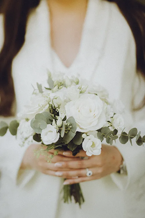 Gros plan du bouquet de la mariée après la cérémonie de mariage à Genève Gros plan sur un bouquet de mariée composé de roses blanches, tenu par la mariée après la cérémonie dans un parc à Genève.