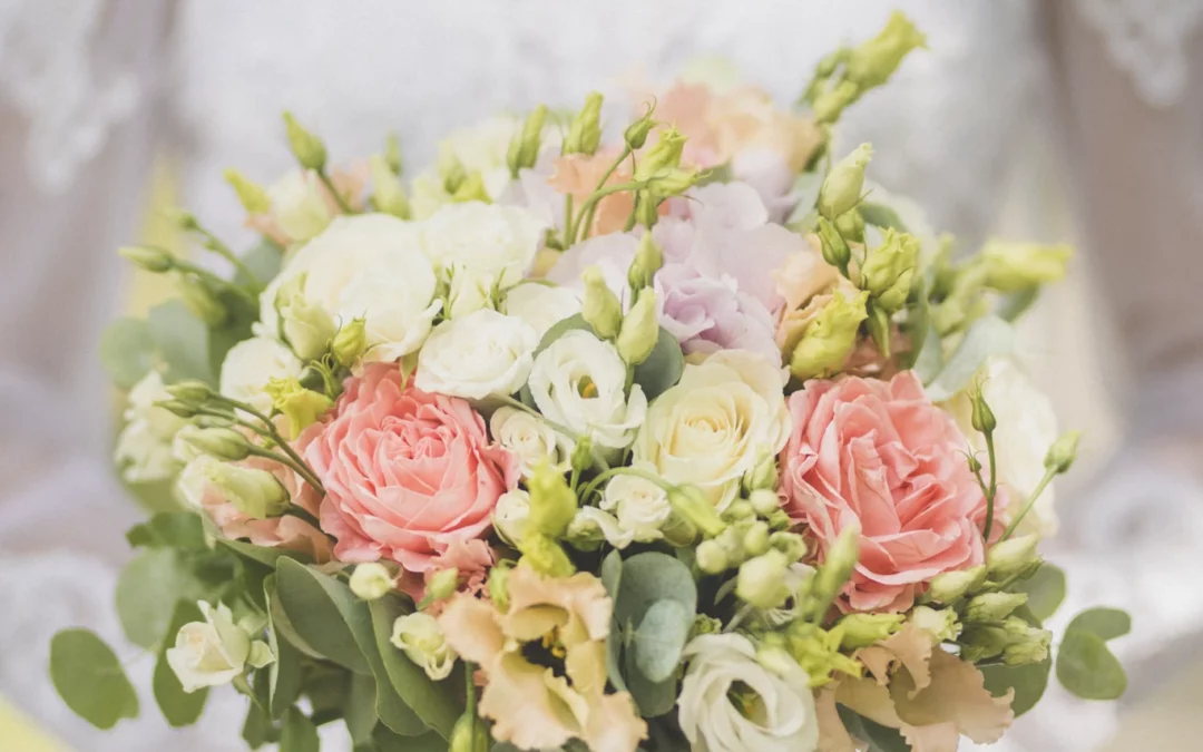 Gros plan du bouquet de la mariée, avec un flou artistique en arrière-plan révélant la mariée le tenant, lors d’une séance photo en forêt près du Château de Faucigny en Haute-Savoie.