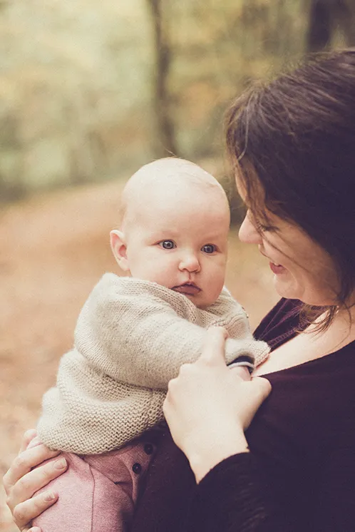 Photographe famille Haute-Savoie : Moment de tendresse en forêt Une maman regardant tendrement son bébé lors d'une séance photo de famille en forêt en Haute-Savoie.